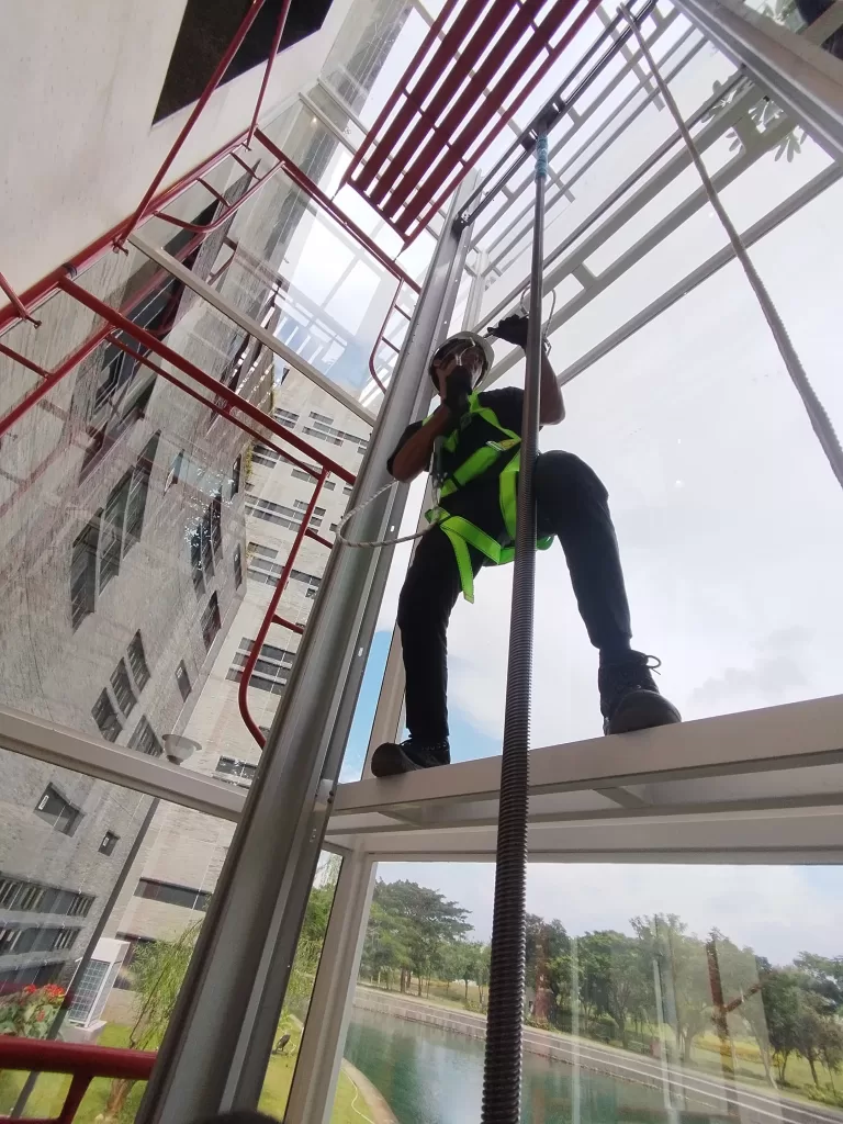 Teknisi memasang lift rumah Kalea saat proses instalasi shaft kaca pada proyek hunian bertingkat