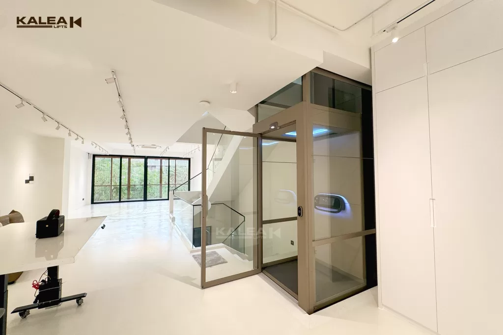 lift rumah mewah Kalea X80 shaft warna champagne dekat dengan tangga dengan pencahayaan alami